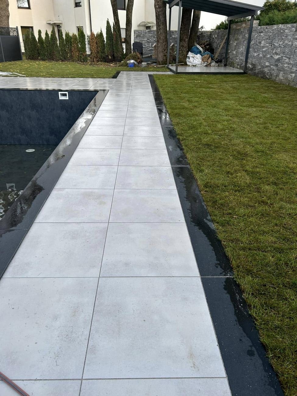 Plattenweg zwischen Pool und Rasen mit dunkler Randeinfassung
